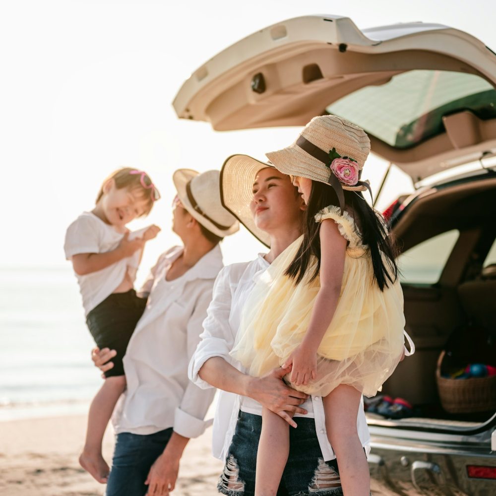 Happy asian family on a road trip in their car. Dad, mom and daughter are traveling by the sea.